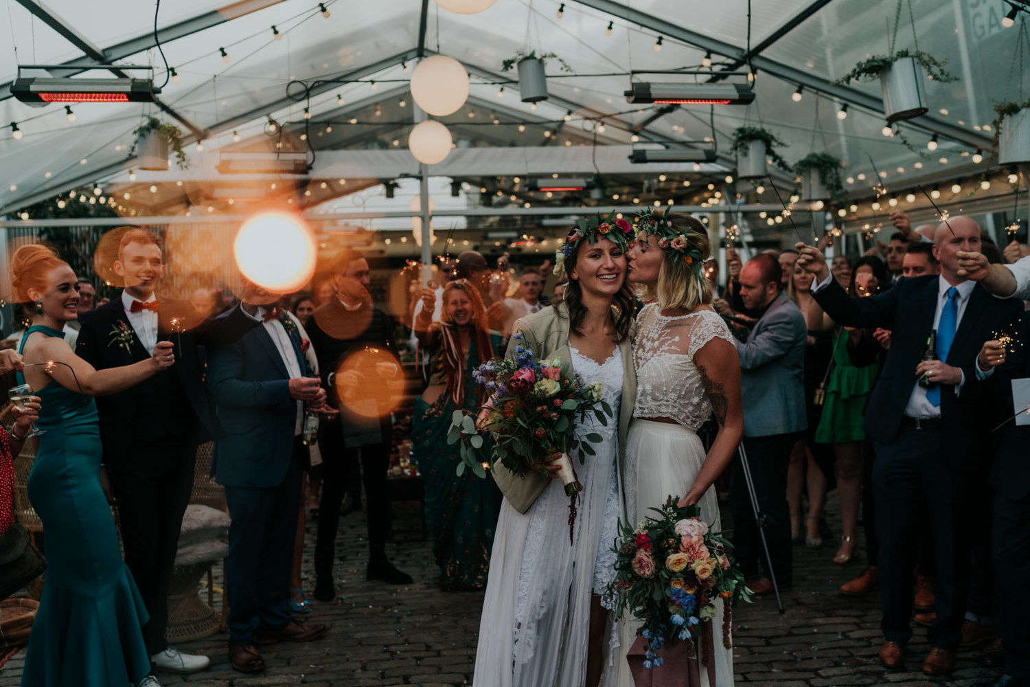 two brides with sparklers and guests