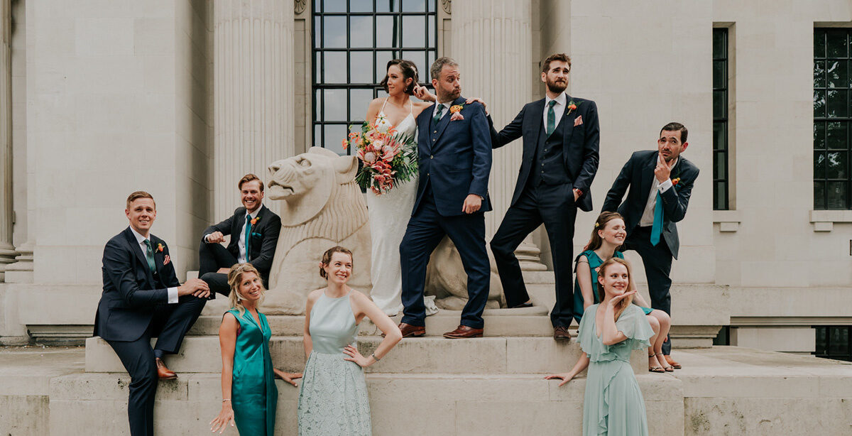 fun wedding photo of bridesmaids and groomsment on the lion outside the old marylebone town hall