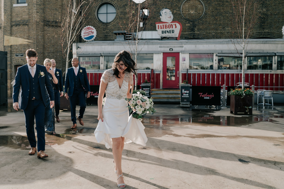 bride and wedding party walking in front of fatboys diner in trinity buory wharf