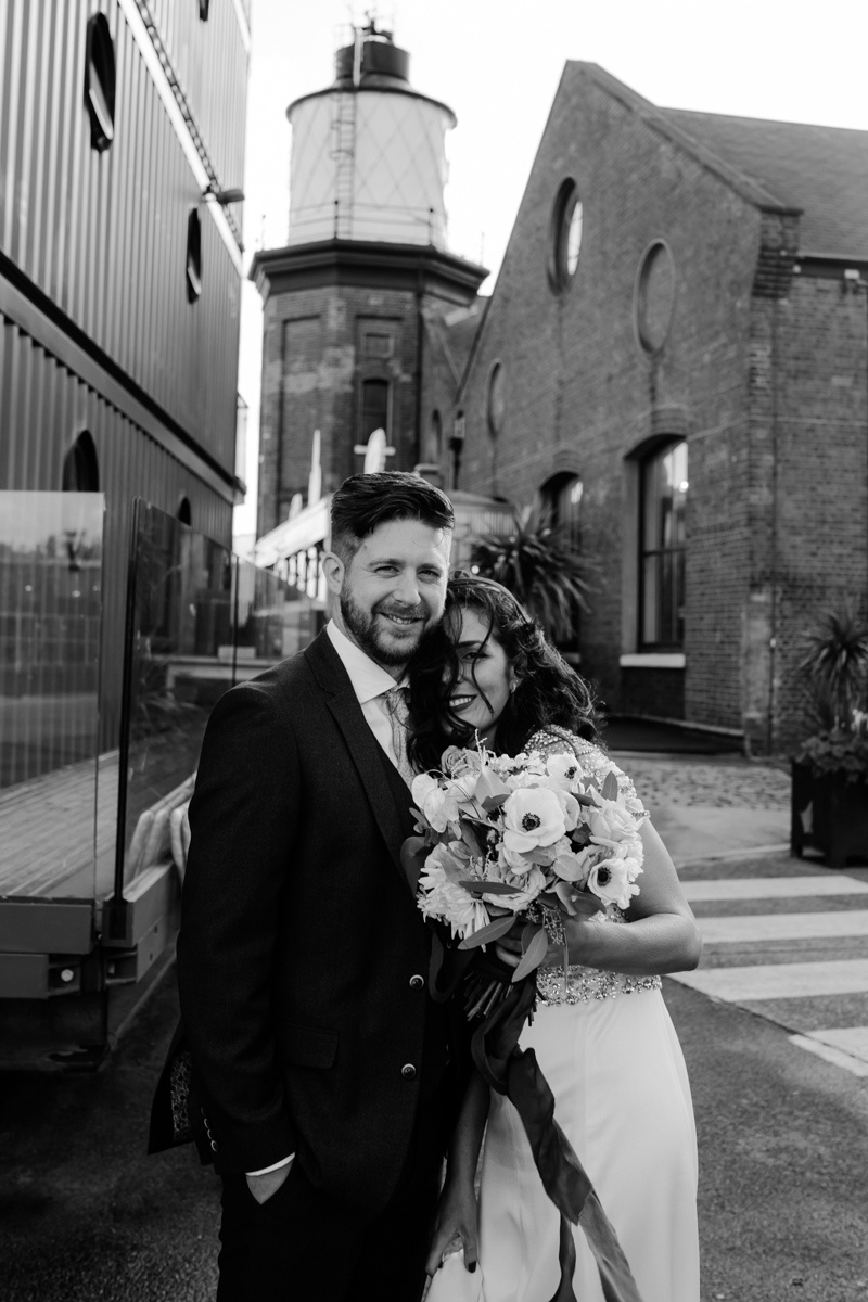bride and groom in front of trinity buoy wharf lighthouse and chainstore