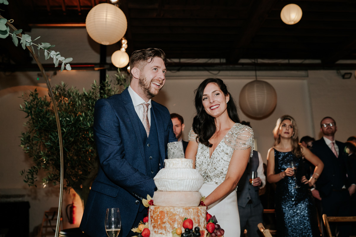 bride and groom smiling and cutting cake of cheese