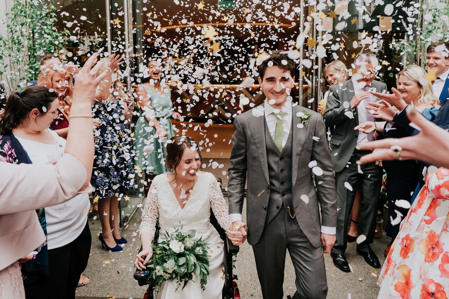bride in a wheelchair and groom showered with confetti