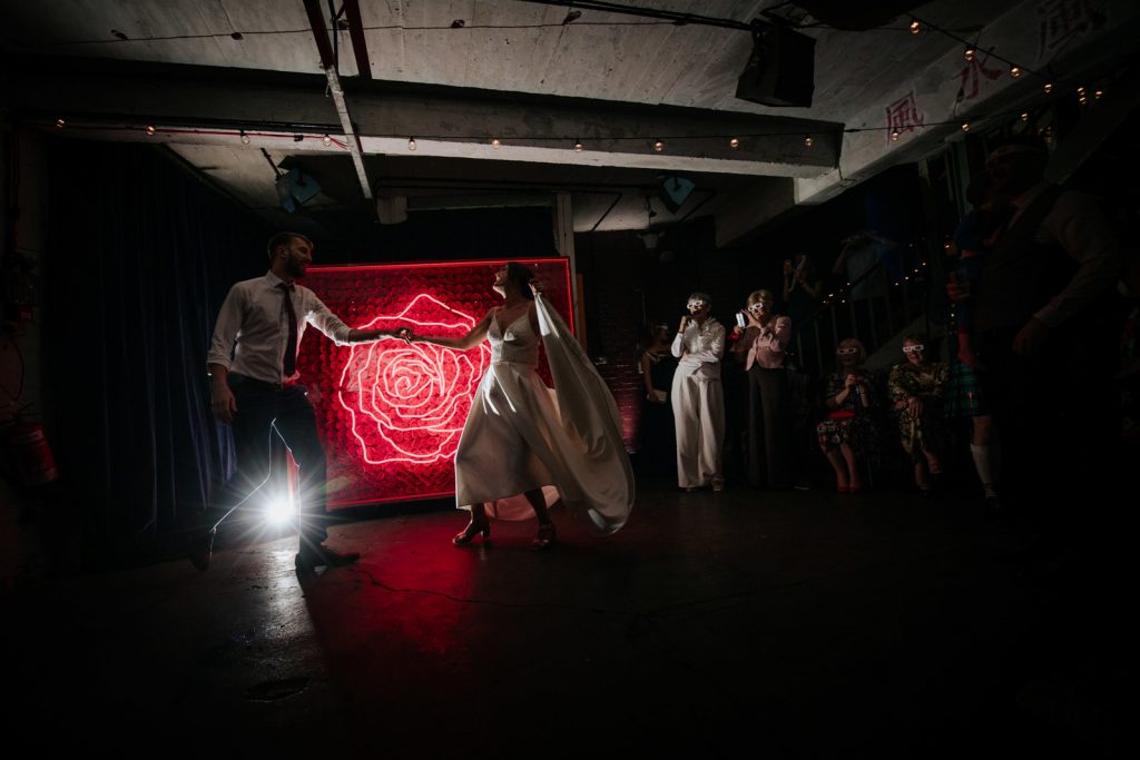 first dance at one friendly place wedding venue with red neon rose sign