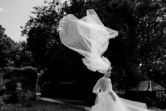 Bride with wind swept veil turning around - artistic documentary wedding photography
