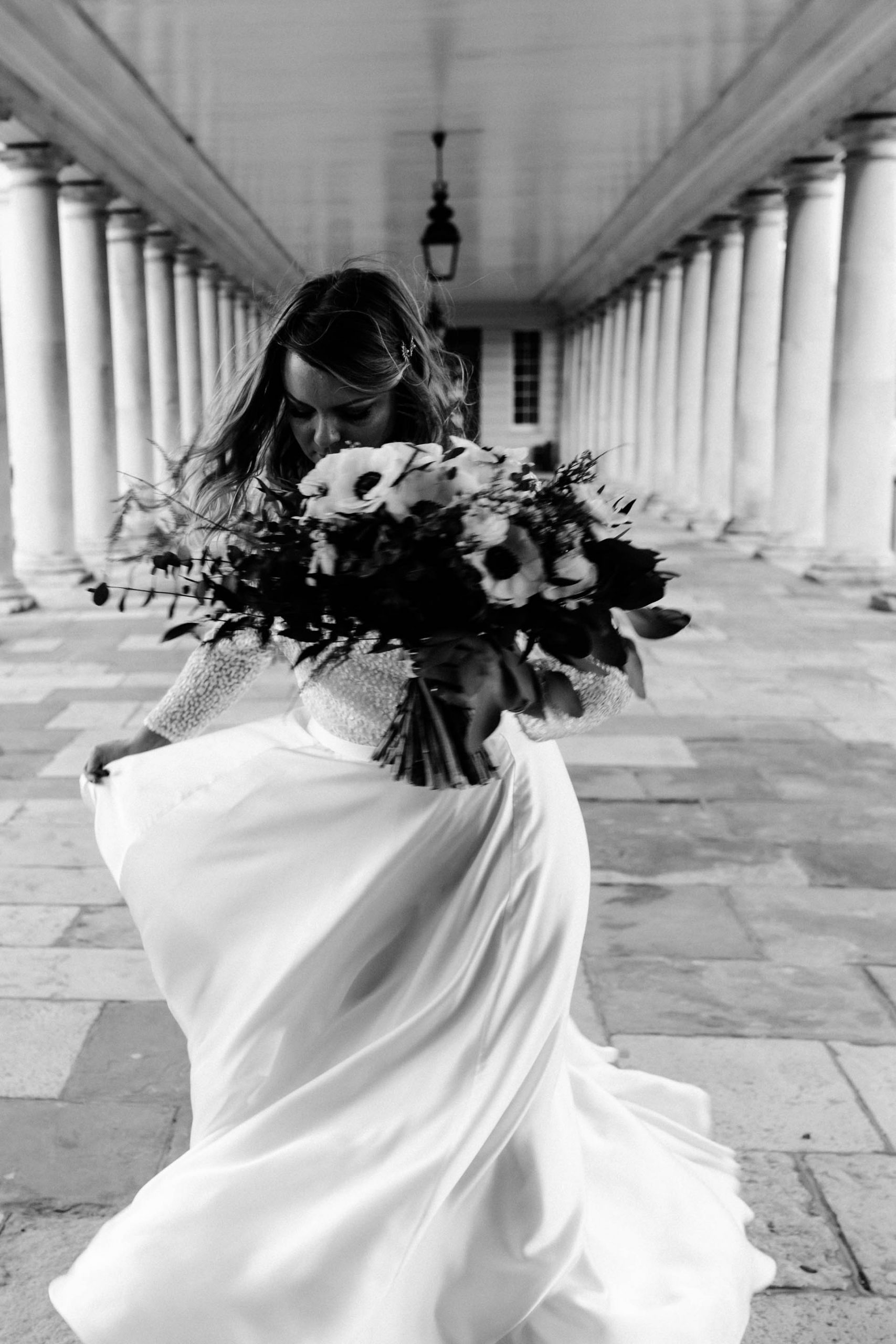 cinematic black and white photo of bride in the colonnade of queens house