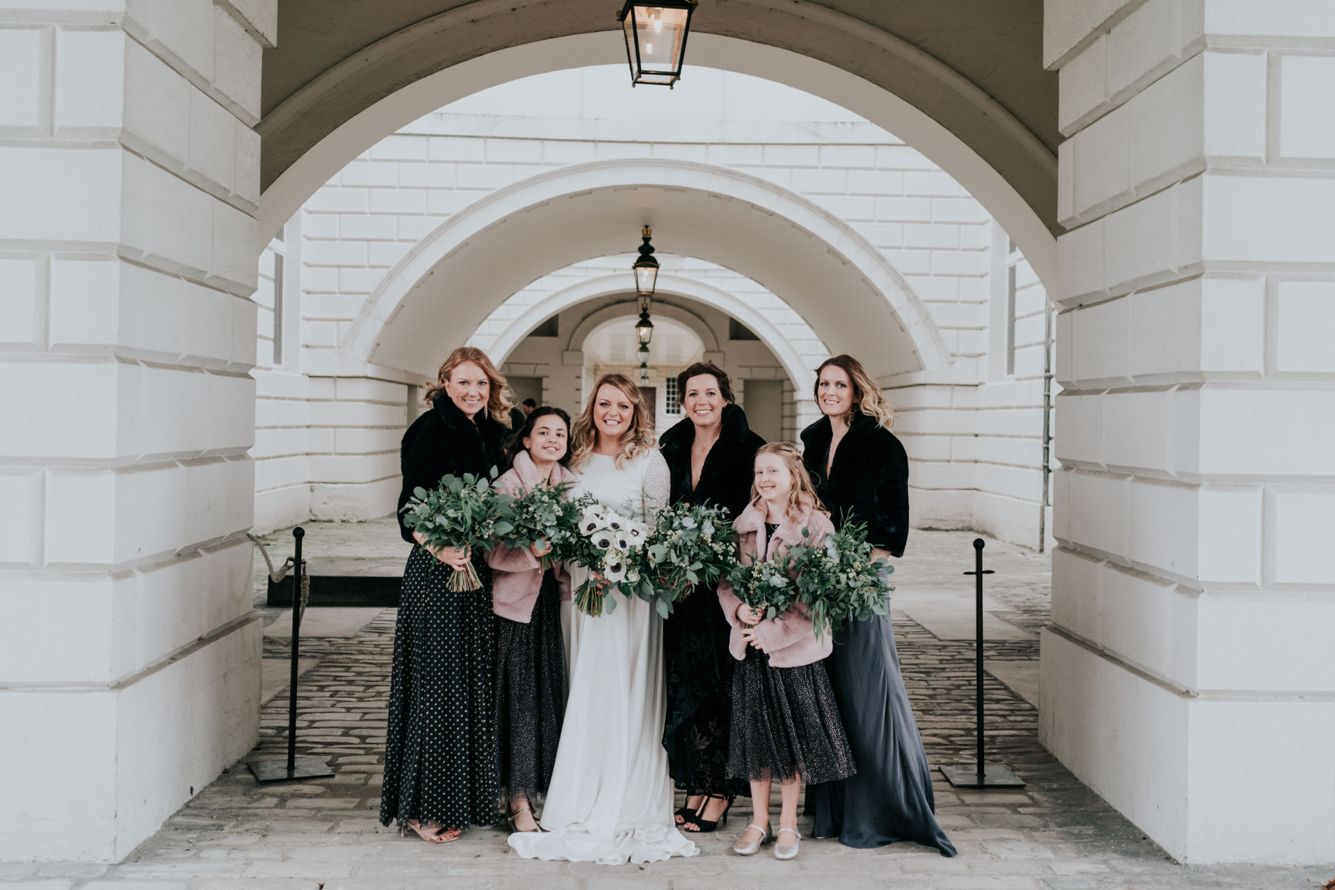 bride and bridesmaids photo with black mismatched dresses and black fur stolen