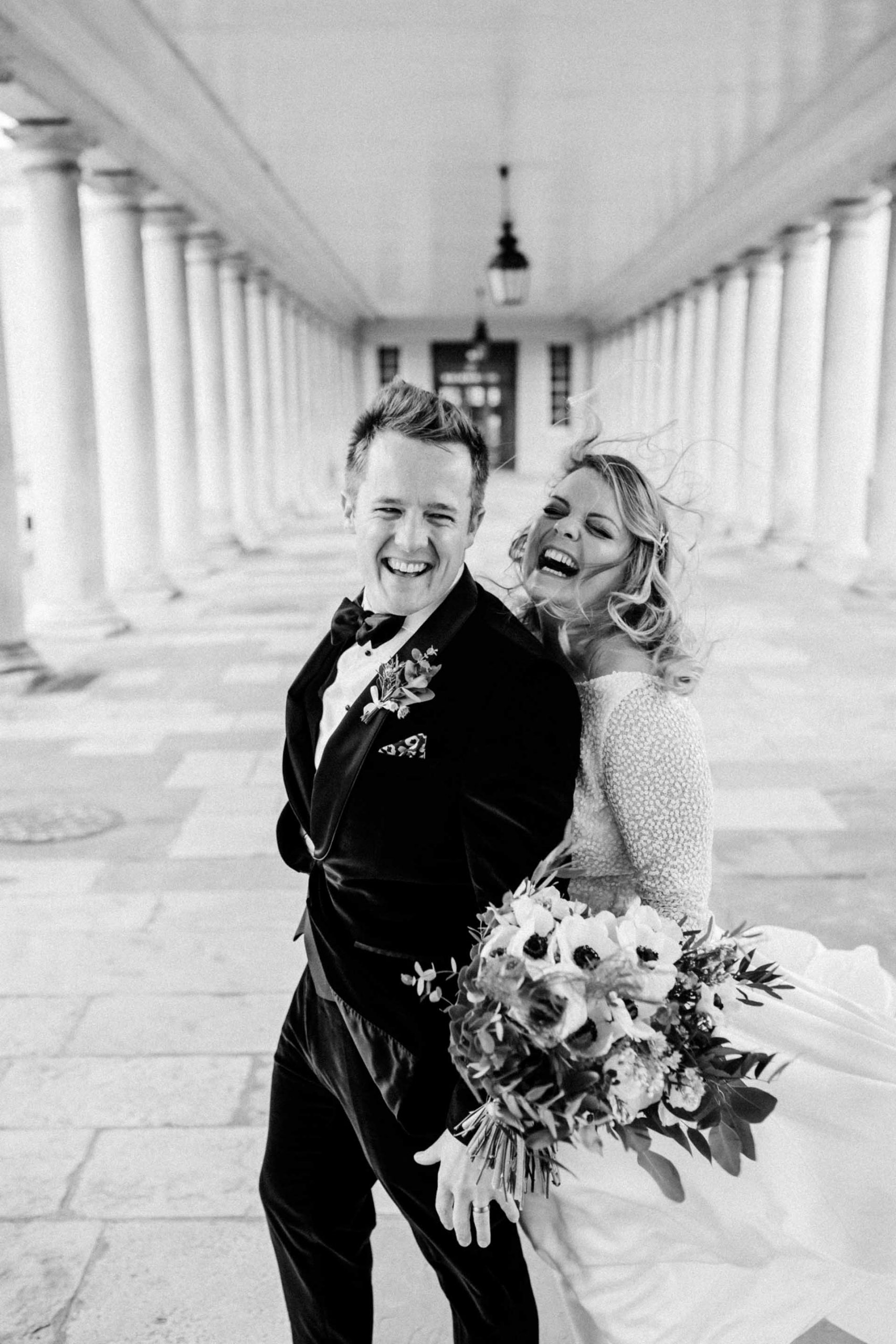bride and groom laughing in the queens house colonnade in black and white