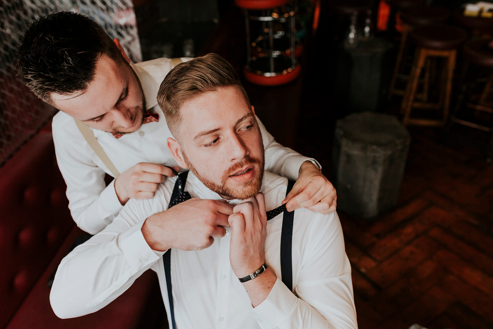 two grooms putting bow tie