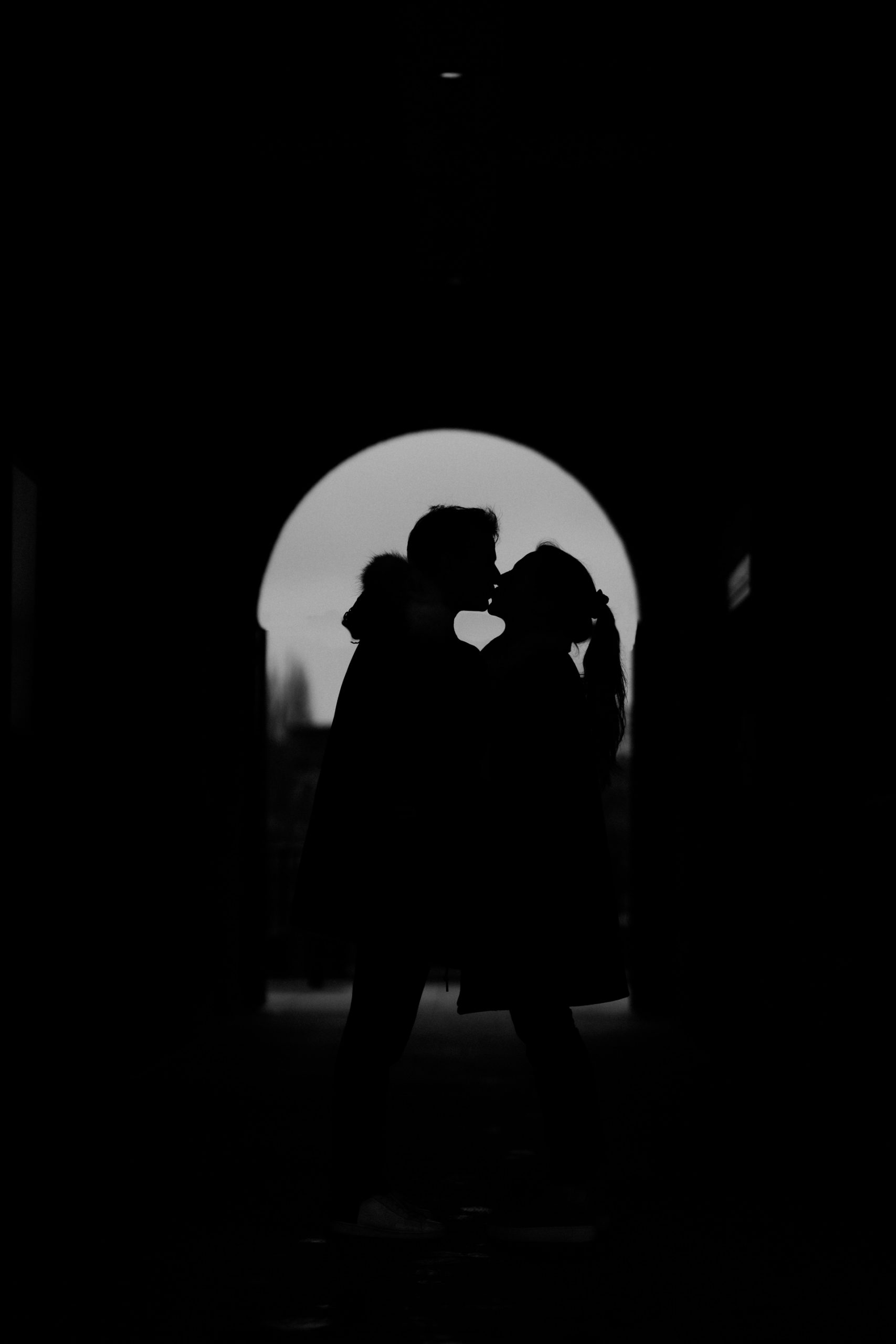 black and white silhouette of couple kissing in door