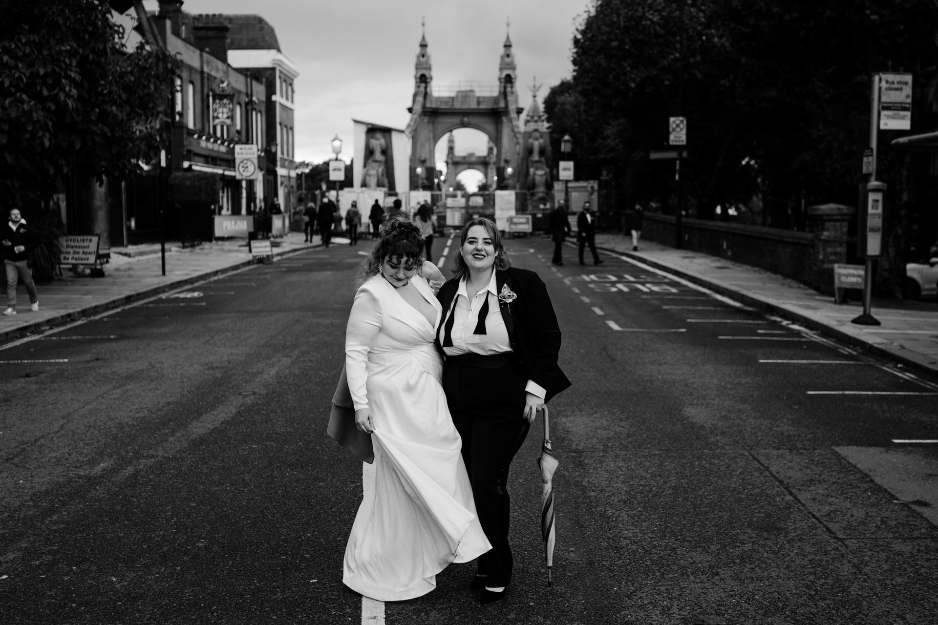 two brides in front of hammersmith bridge