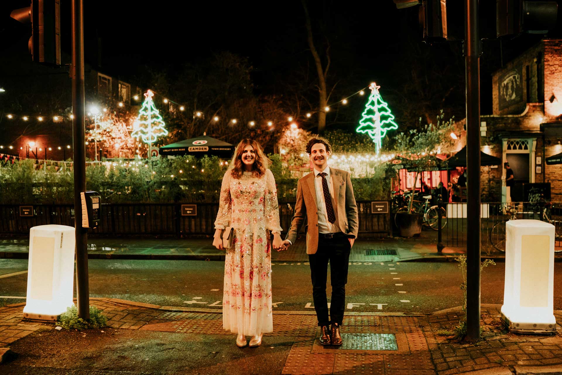 nightime photo of bride and groom with christmas tree neon sign
