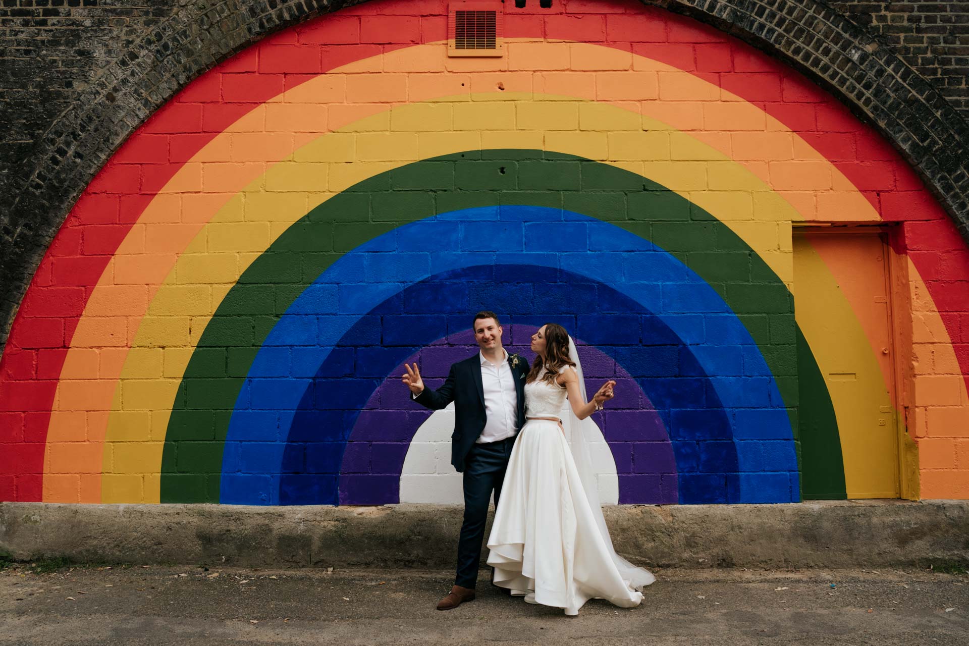 rainbow mural outside of 100 barrington with bride and groom posing