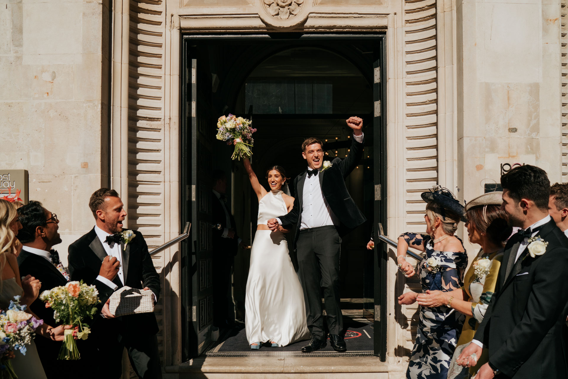 bride and groom exiting ballroom 1901 with hands up in the air