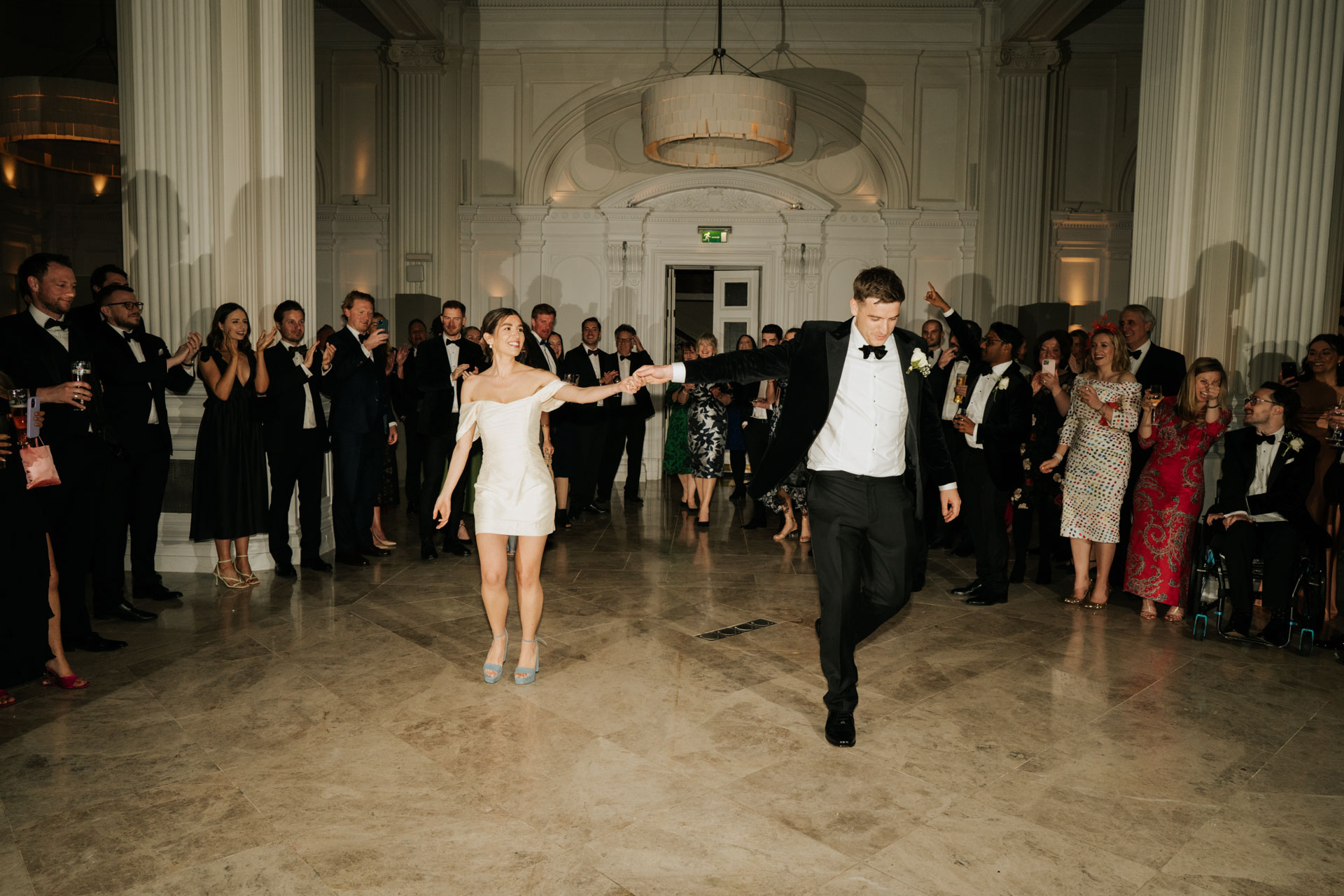 bride in short dress and groom in tux enter 1901 ballroom wedding venue