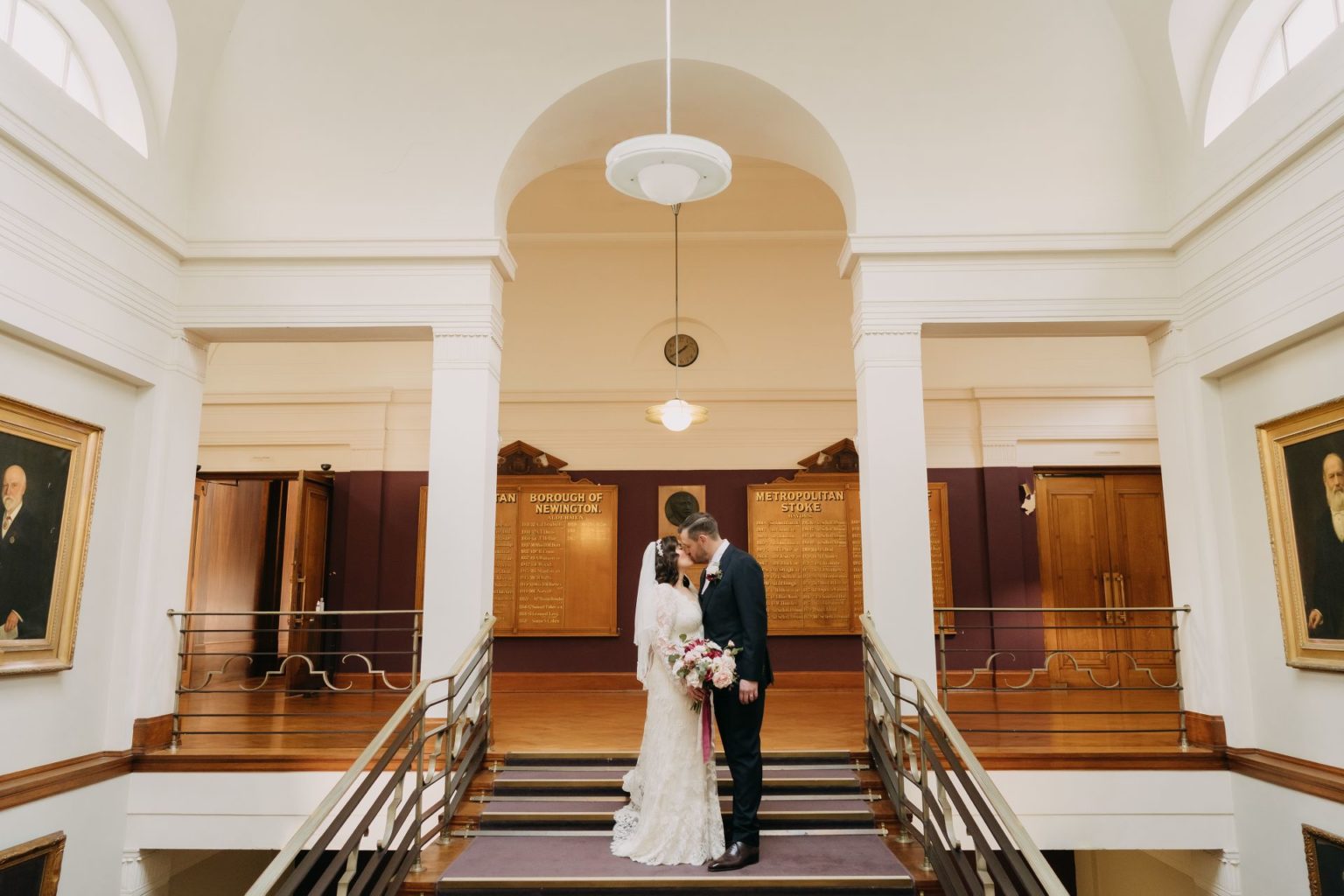 bride and groom kissing on steps of stoke newington town hall after their wedding 