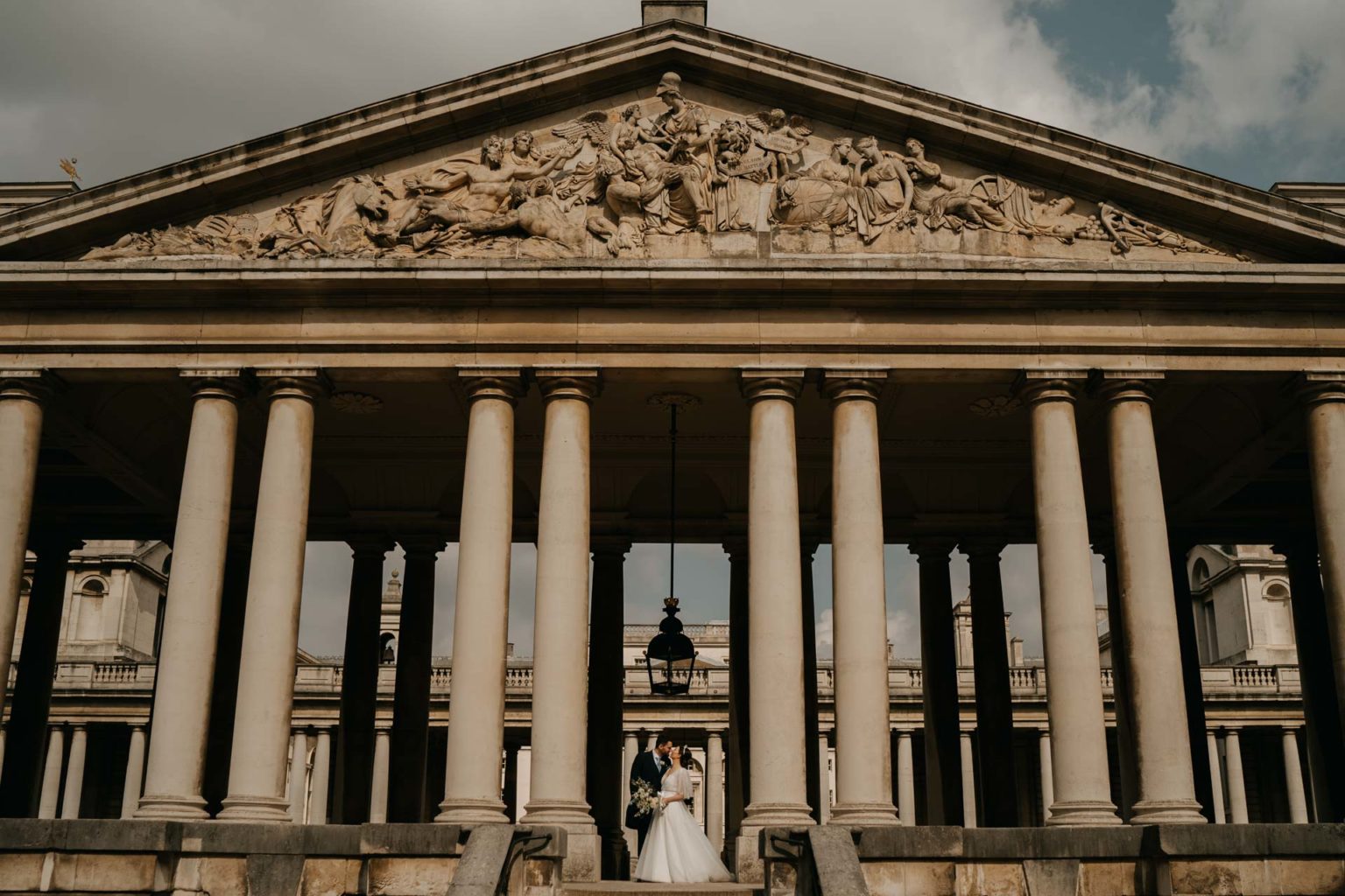 bride and groom kissing in the colonnade of naval college in greenwich by admirals house wedding photographer