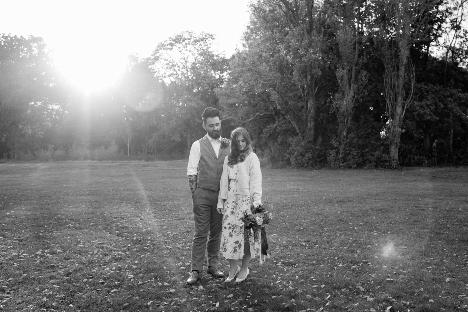 best wedding photography with bride and groom looking down with a sunset flare behind them