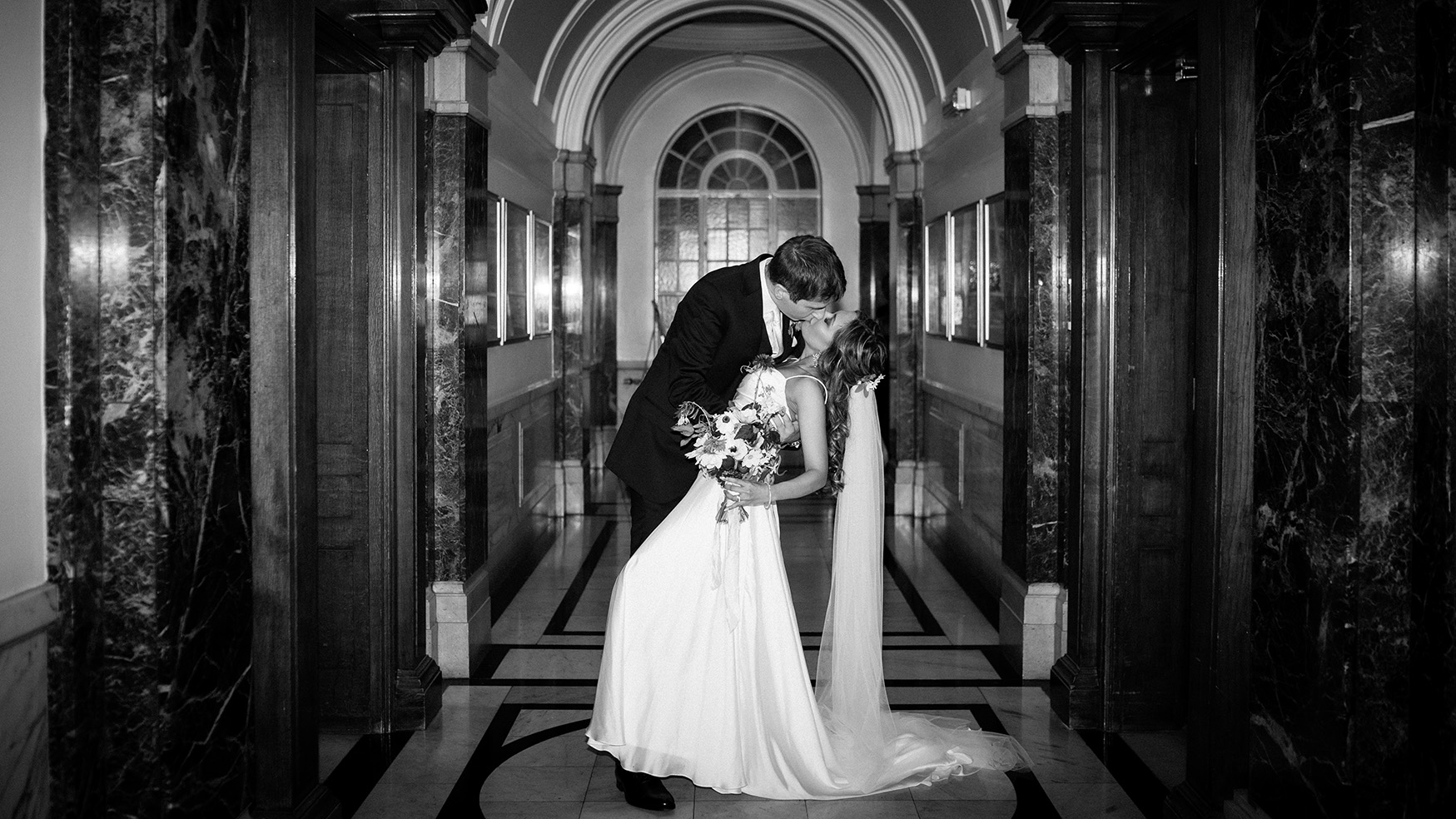 groom kissing bride in islington town hall corridor at night