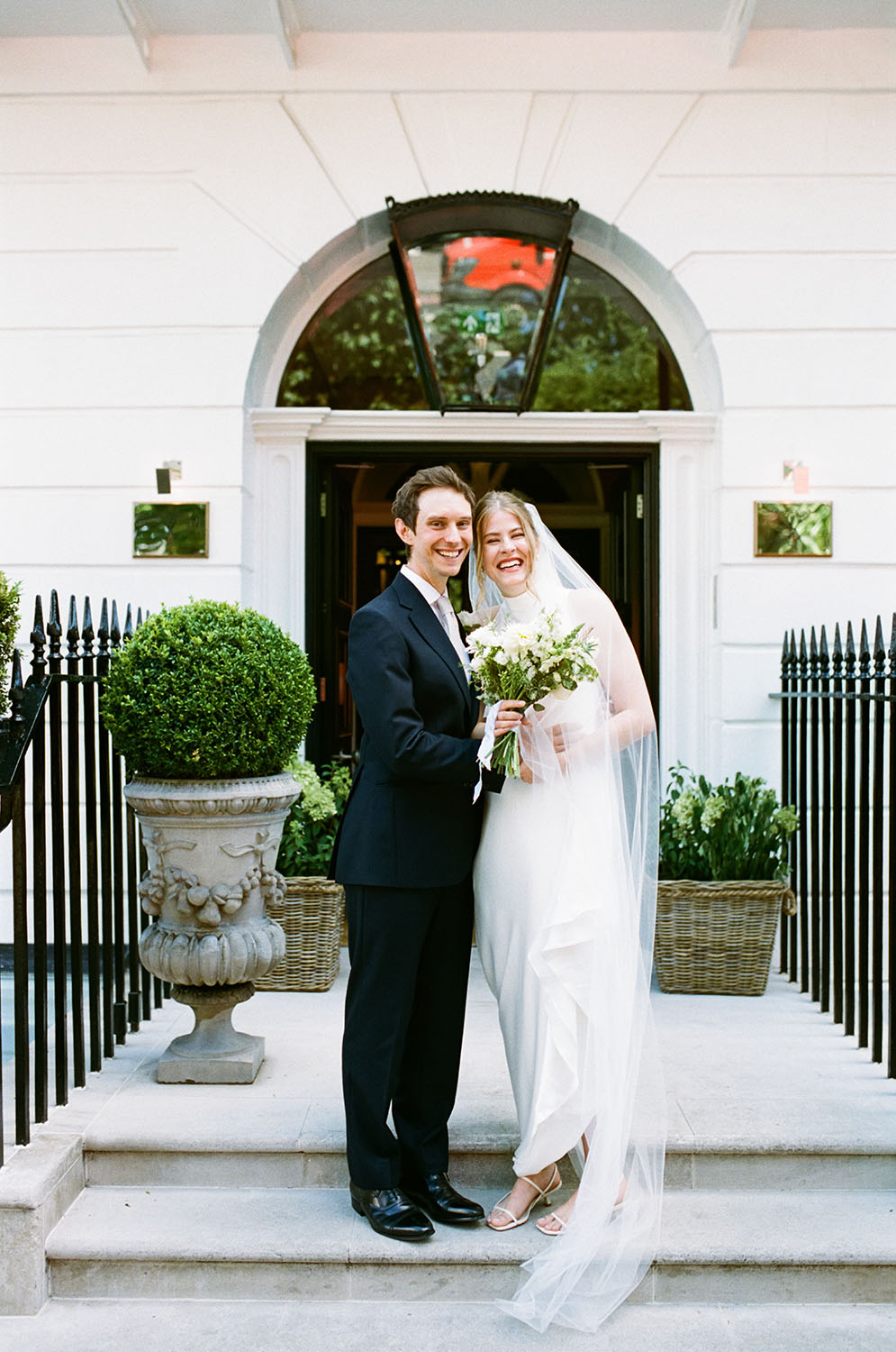 bride and groom smiling for film camera outside dorset square hotel in london