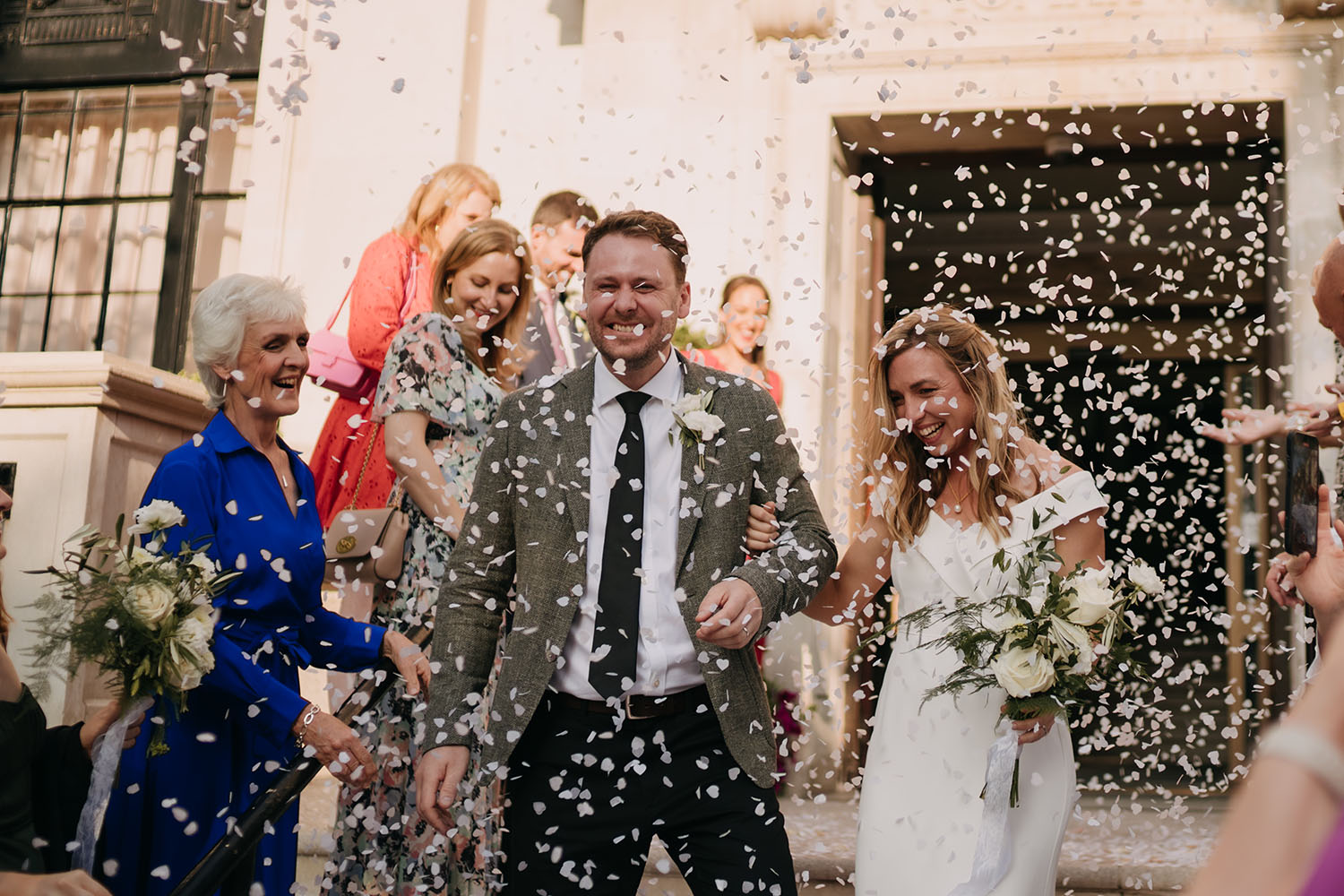bride and groom smiling in confetti shower at islington town hall after their micro wedding