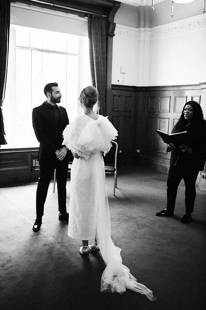 film wedding photo of bride with a dress with a large bow at ceremony in the richmond suite at the islington town hall