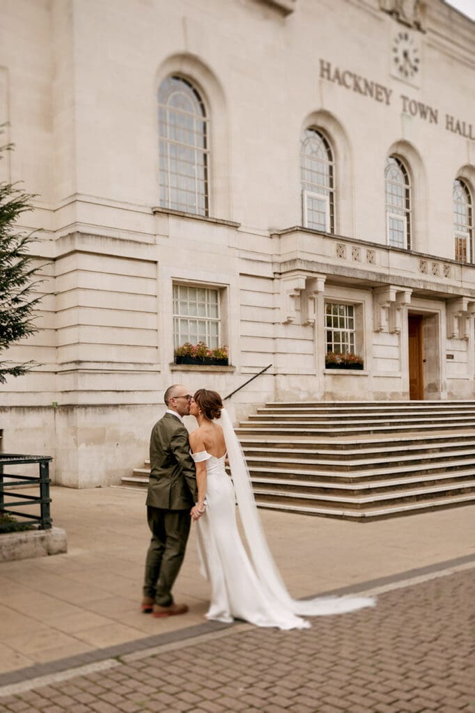 bride and groom kissing in front of hackney town hall