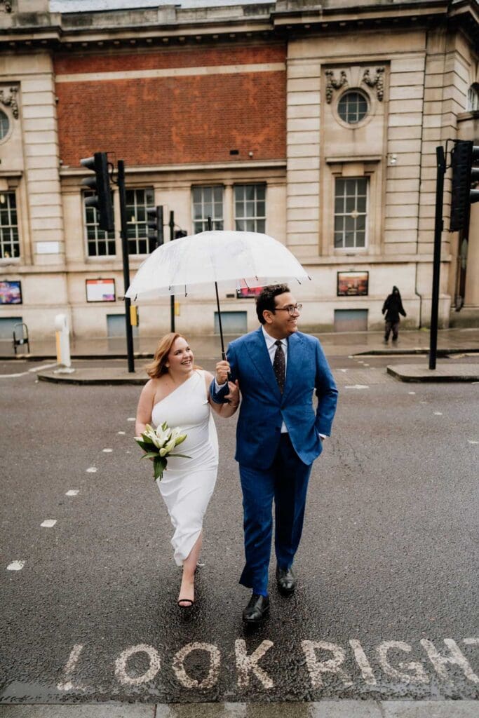 bride and groom walking on london hackney street under a white umbrella