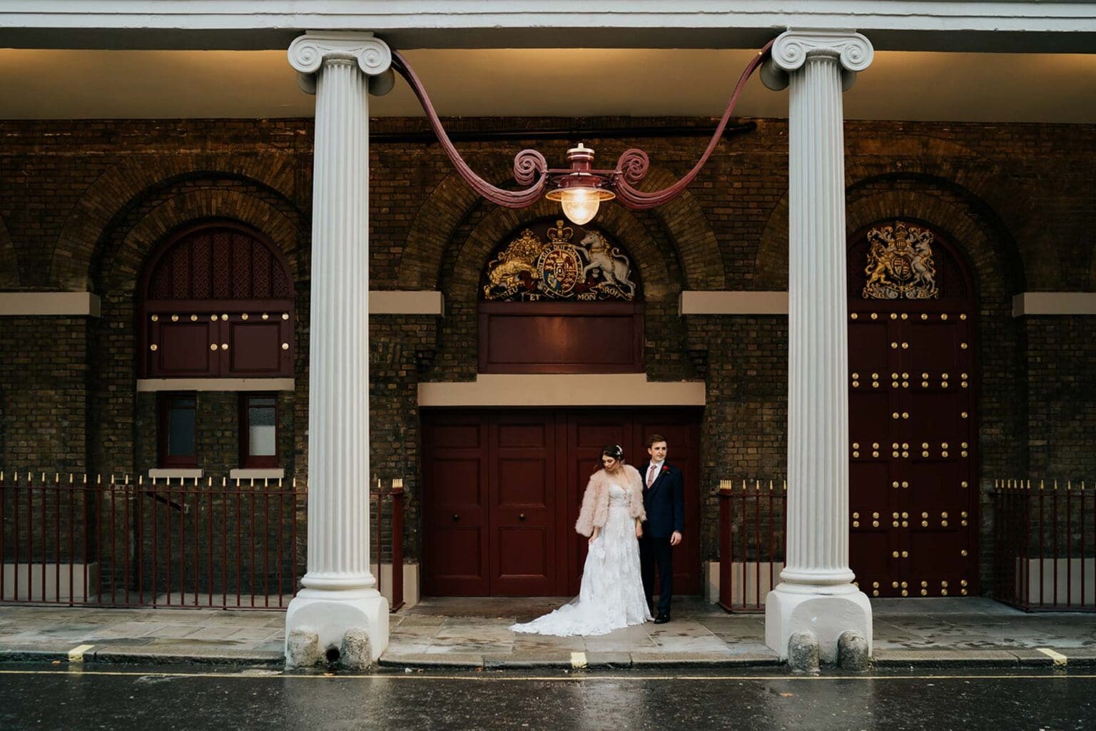 bride and groom posed under a sheltered roof to combat rain on wedding day in Holborn London