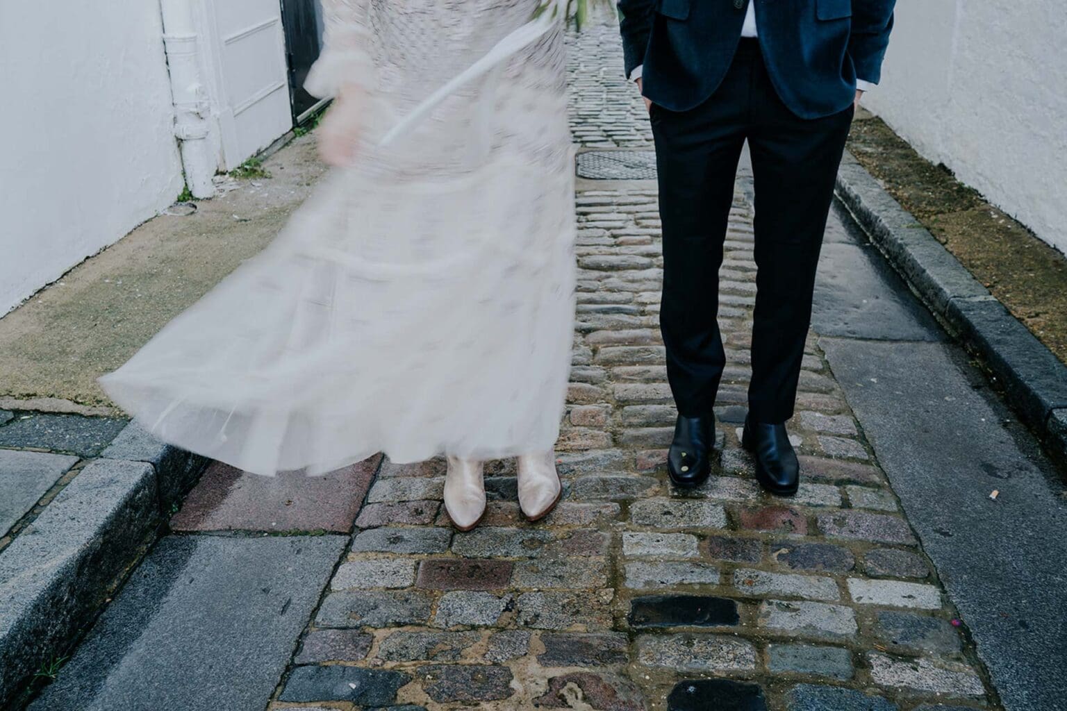 close up photo of bride silver boots and grooms shoes on wet london street cobblestones on a rainy wedding day