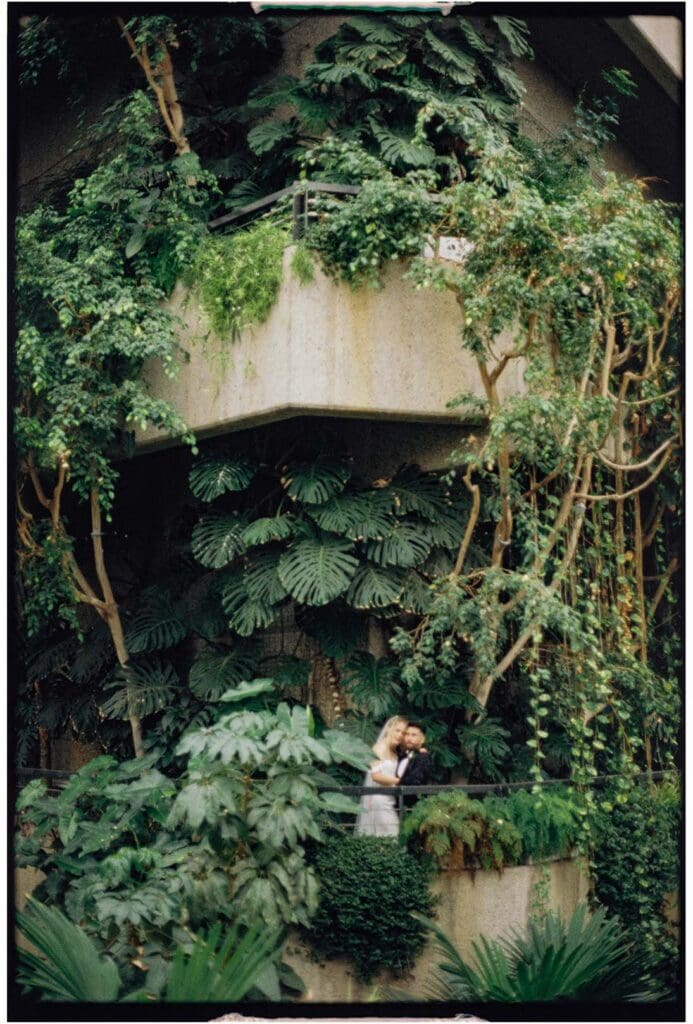 bride adn groom in barbican conservatory surrounded by greenery and foliage