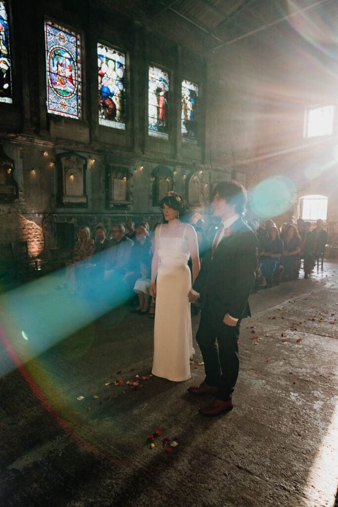 film wedding photo of a couple getting married at asylum chapel with strong light and colour leaks seeping into the frame