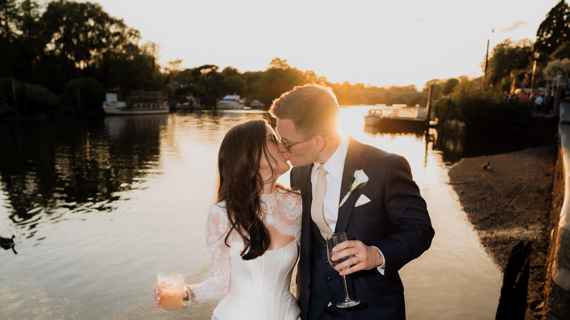 Bride and groom kissing with a sunset over the thames at Scott's in Richmond wedding